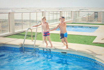Two boys fun jumping into the swimming pool, shot through the underwater package.