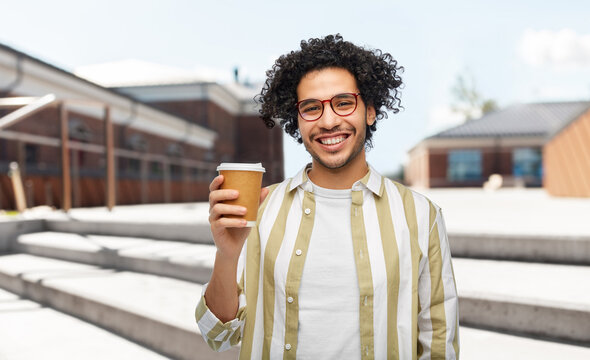 drinks and people concept - smiling young man in glasses with takeaway coffee cup over city street background
