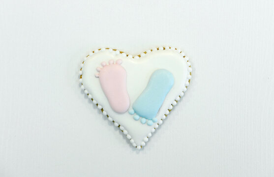 Gingerbread in the shape of a heart with painted baby heels in blue and pink