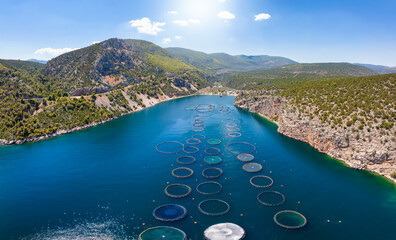 Aerial view of a large fish farm at a smal bay in the blue, mediterranean sea in Greece