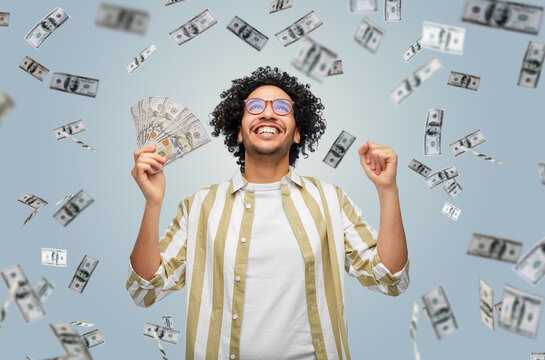 finance, currency and people concept - happy man holding hundreds of dollar money banknotes celebrating success over grey background