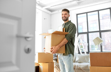 moving, people and real estate concept - happy smiling man holding box with stuff at new home