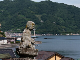 港を見下ろす丘に座る石の仏像
