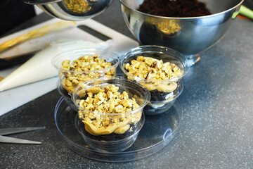 The process of preparing a multi-layered dessert. Confectioner lays out layers of caramel, biscuit and nuts in a plastic mold