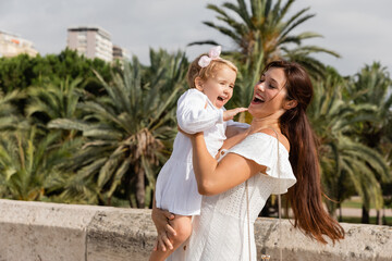 Happy woman holding child in summer dress in Valencia.