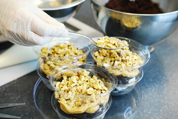 The process of preparing a multi-layered dessert. Confectioner lays out layers of caramel, biscuit and nuts in a plastic mold