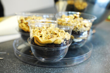 The process of preparing a multi-layered dessert. Confectioner lays out layers of caramel, biscuit and nuts in a plastic mold
