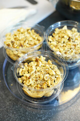 The process of preparing a multi-layered dessert. Confectioner lays out layers of caramel, biscuit and nuts in a plastic mold