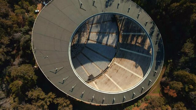 Aerial top down spinning over Quinta Vergara Amphitheater surrunded by tree forest in park, Vi&ntilde;a del Mar hillside, Chile