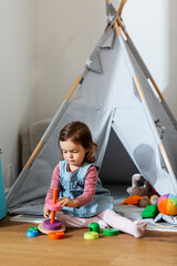 childhood, leisure and people concept - little baby girl playing with toy pyramid at home © Syda Productions