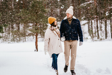 people, love and leisure concept - happy smiling couple walking in winter forest