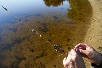 Close up view of males hand prepare  tackle for feeder fishing on the river.