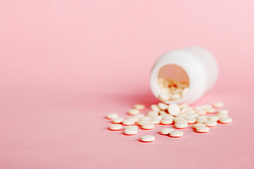 Medicine bottle and white pills spilled on a light background. Medicines and prescription pills flat lay background. White medical pills and tablets spilling out of a drug bottle