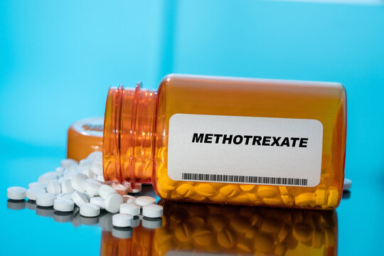 Methotrexate white medical pills and tablets spilling out of a drug bottle. Macro top down view with copy space.