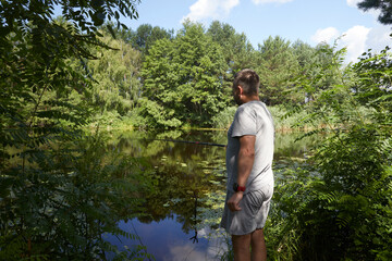 Naklejka premium Caucasian adult man fishing on the river with beautiful view of landscape.