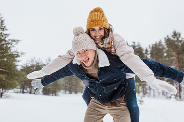 people, season, love and leisure concept - happy couple having fun in winter park