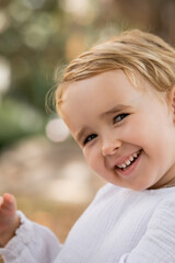 Portrait of smiling toddler child looking at camera outdoors.