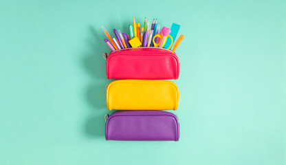 Back to school concept. Bright school pencil case with filling school stationery, pens, pencils, scissors, rule. School accessories on blue background. Flat lay, top view, copy space - obrazy, fototapety, plakaty