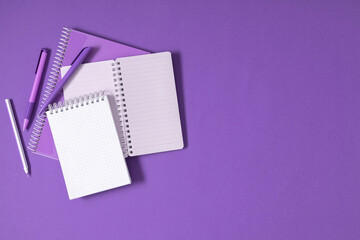 Purple pencils and notebooks on purple background. Back to school. Office desk with copy space. Flat lay, top view