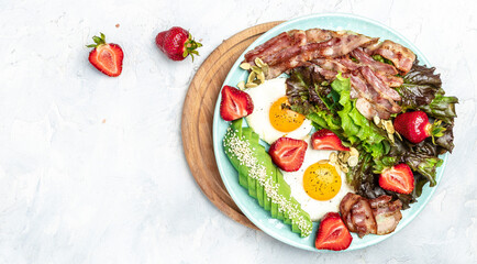 Ketogenic diet food, Fried egg bacon with avocado, strawberries and fresh salad on a light background. healthy meal concept, Long banner format. top view