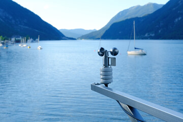 modern device anemometer over alpine lake controls parameters, meteorological equipment measures speed of movement of air masses, humidity levels, atmospheric pressure, wind strength and direction - obrazy, fototapety, plakaty
