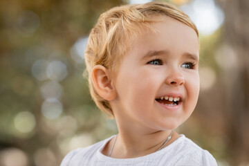 Portrait of happy baby girl looking away outdoors.