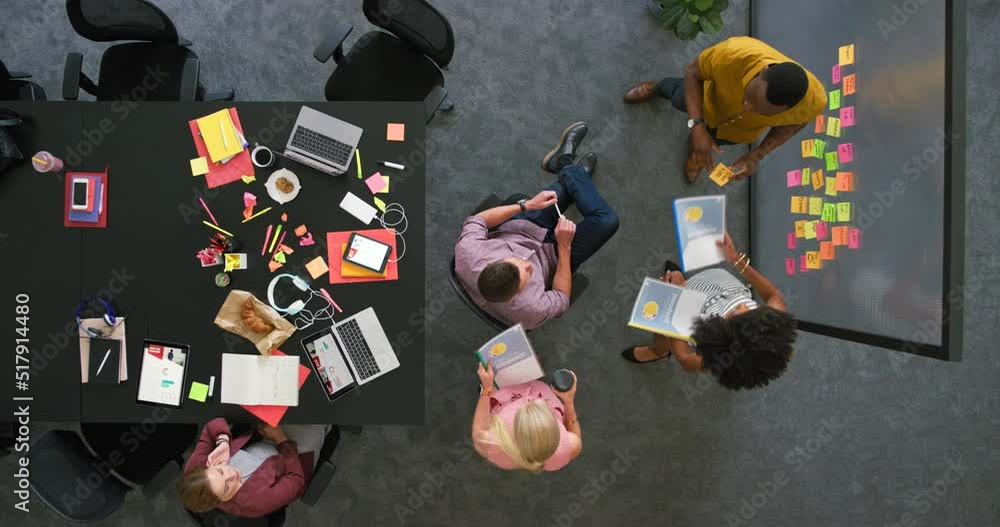 Aufkleber Designers brainstorming and planning ideas with notes on a glass wall in an office from above. Top view of dedicated colleagues collaborating to discuss reports and a marketing strategy for a project
