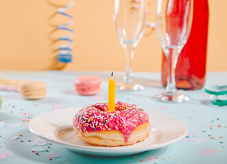 Delicious donut with pink icing and bottle of wine, glasses and macaroons on the background. Birthday concept.