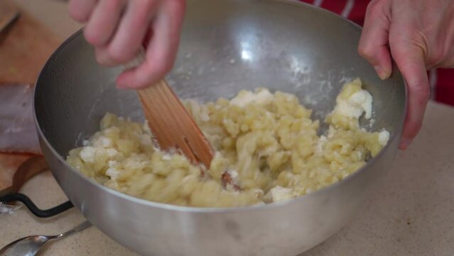 Woman Mixing Bryndza Cheese To Coat The Hot Halusky Dumplings On The Bowl. - close up