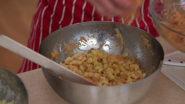 Female Hands Mixing Strapacky Ingredients In A Bowl, Then Add Sauerkraut (Fermented Cabbage Cut Finely). close up