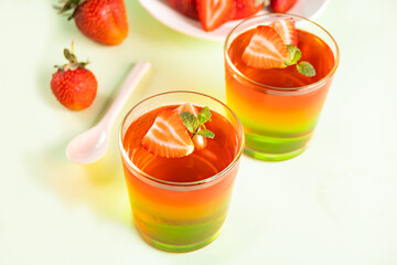 Glasses of tasty summer dessert layered colorful jelly with fresh strawberries