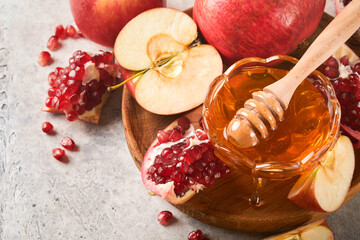 Rosh Hashanah. Pomegranate, apples and honey traditional products for celebration on rustic grey...