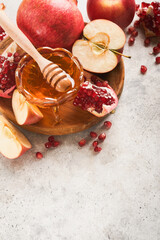 Rosh Hashanah. Pomegranate, apples and honey traditional products for celebration on rustic grey background. Jewish Autumn Rosh Hashana celebration. Jewish holiday Rosh Hashana design. Selective focus