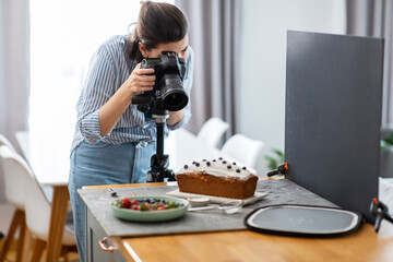 blogging, profession and people concept - female food photographer with camera photographing cake...