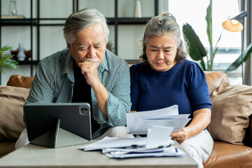 old retired asian senior couple checking and calculate financial billing together on sofa involved...