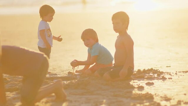 4K SlowMo - wonderful family - father, mother and 4 boys (1-8 years old) - brothers have fun playing in the sand with each other
