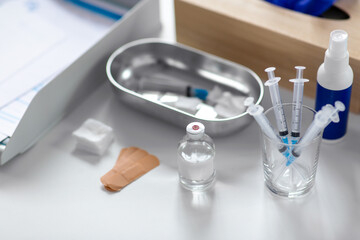 medicine and healthcare concept - close up of syringes, drug in jar and other stuff on table at hospital