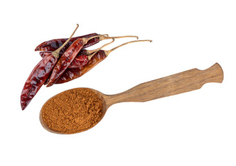 Top view of several hot pepper pods and a wooden spoon with ground pepper on a white background.