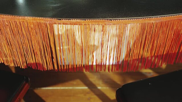 Close-up vintage style floor lamp torchere with orange fringe, slow motion.