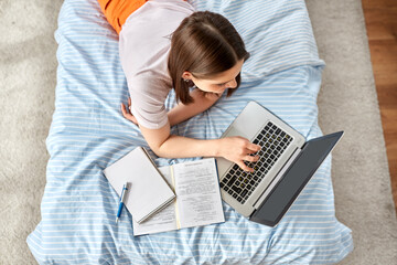 school, online education and e-learning concept - teenage student girl with laptop computer writing...