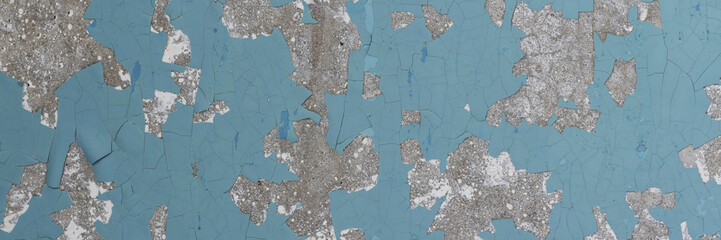 Peeling paint on the wall. Panorama of a concrete wall with old cracked flaking paint. Weathered rough painted surface with patterns of cracks and peeling. Wide panoramic grunge texture for background