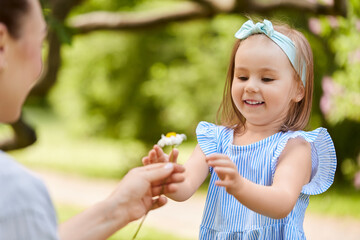 Obraz premium family, motherhood and people concept - happy mother and little daughter with chamomile flower at summer park or garden