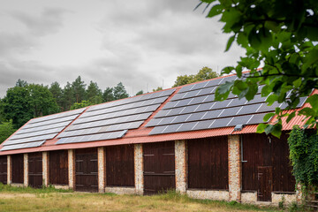 Fototapeta na wymiar A huge brick barn with solar panels on the roof. Horse stud in Florianka. Beautiful rural landscape