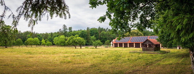 Panorama of the run for horses. Brick barn with photovoltaic panels on a corrugated roof. Beautiful...