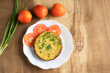 Egg breakfast food omelet has vegetable in plate on wood table.