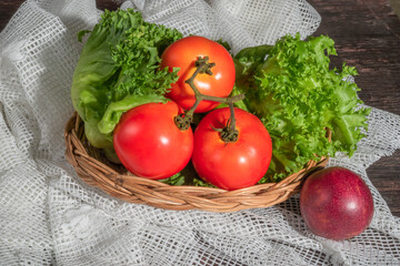 Healthy food salad lettuce tomato in basket and passion fruit on wood background.