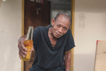 A middle aged filipino man offers a bottle of beer to someone. Hospitable and friendly local folk...