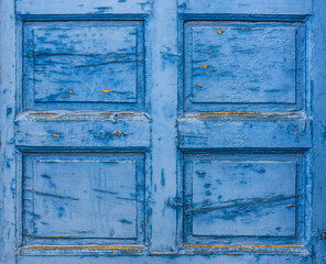 Old blue wooden door part background. Weathered wooden surface with squares, scratches and peeling paint. Rustic vintage backdrop