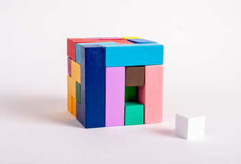 Wooden cube from multicolored blocks with one missing element. Construction last step concept. Kids...
