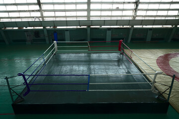 Box training interior. Punching bag. Boxing Ring and Fitness Gym. blue sandbag is hanging in front...